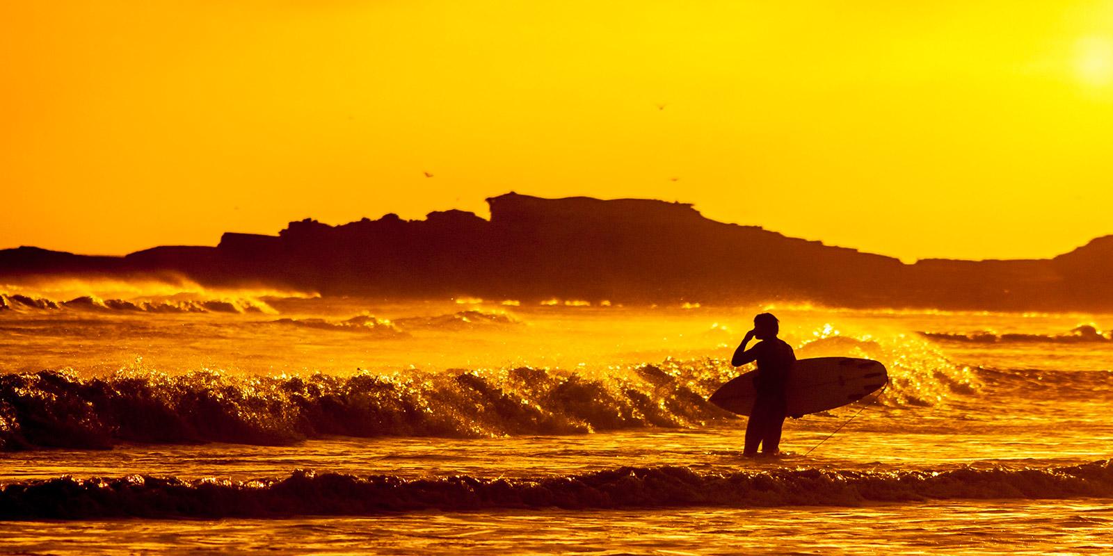 Surfer looking out at the sea with a surfboard in hand - Deaf IT Conference #event #deafit